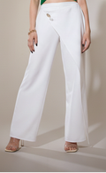 Woman wearing a green top and white pants against a plain background