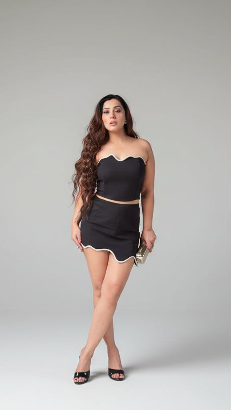 Woman wearing a black outfit with a strapless top and skirt on a gray background